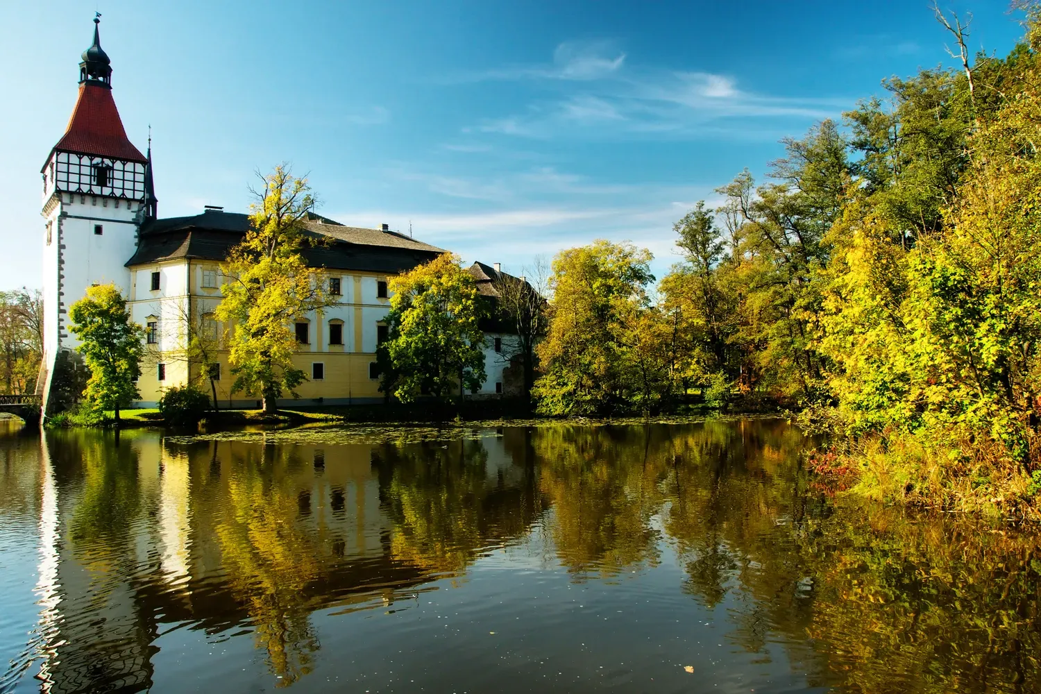 Autumn view of Blatná chateau with its tower reflected.