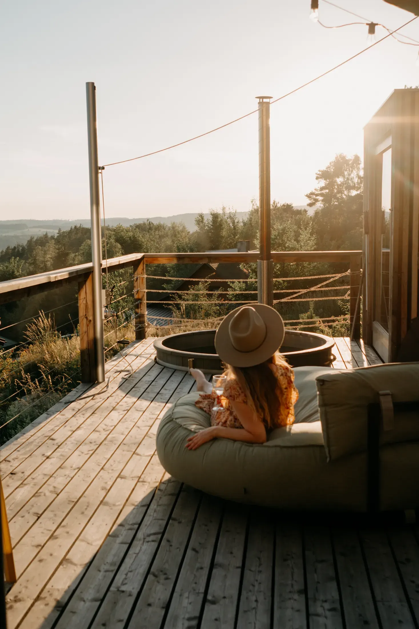 A woman on a bean bag beside the hot tub on the terrace during golden hour.