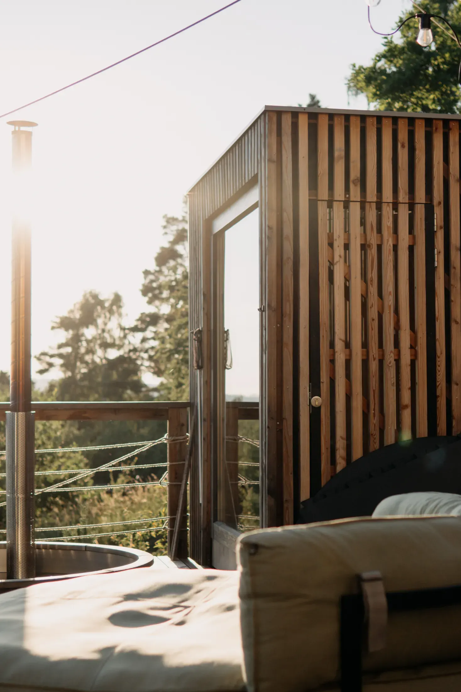 The outdoor sauna with glass doors on the terrace during golden hour.