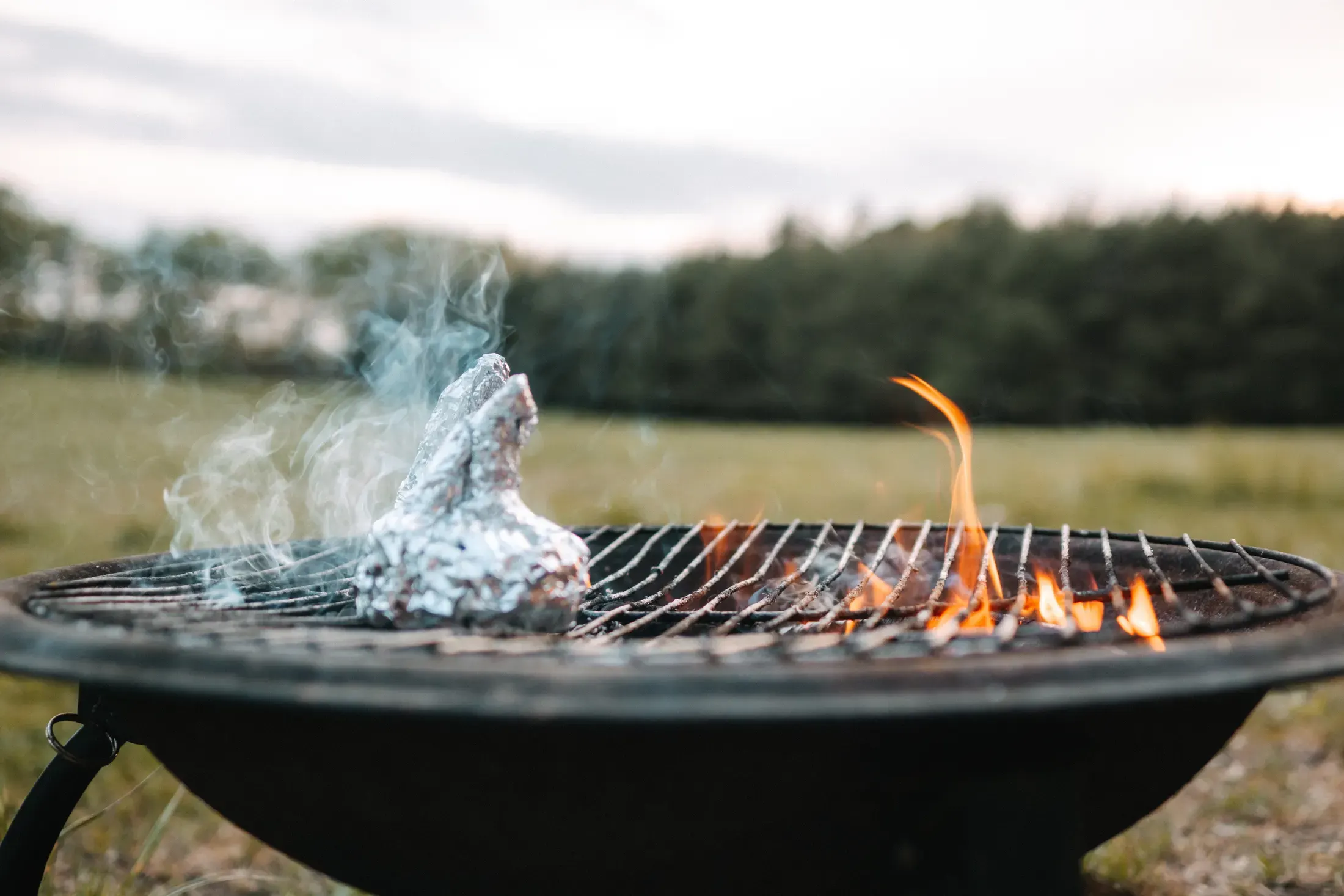 Outdoor fire pit with a grill and flames by the wagon.